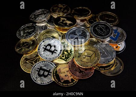 Horizontal view of cryptocurrency tokens, including Bitcoin, Ethererum Ripple, and Litecoin saw from above on black background. High quality photo