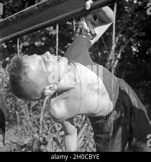 Ein Junge trinkt Wasser aus einer Leitung im Hitlerjugend Lager, Österreich 1930er Jahre. A boys drinking water at the Hitler youth camp, Austria 1930s. Stock Photo