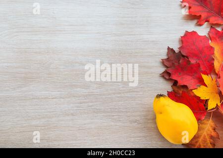 Autumn decor from leaves and quince on a wooden background. Flat lay autumn composition with copy space. Stock Photo