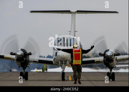 210122-N-EJ241-2025    MISAWA, Japan (Jan. 22, 2021) – Aviation Boatswain’s Mate (Handling) 3rd Class Niko Andre Manuel, assigned to Naval Air Facility (NAF) Misawa, directs the crew of a C-12 Huron, assigned to Naval Air Facility Atsugi, during a transportation mission. NAF Misawa provides aviation and ground logistics support and services to all permanent and transient U.S. Navy and U.S. Marine Corps forces in Northern Japan. Stock Photo