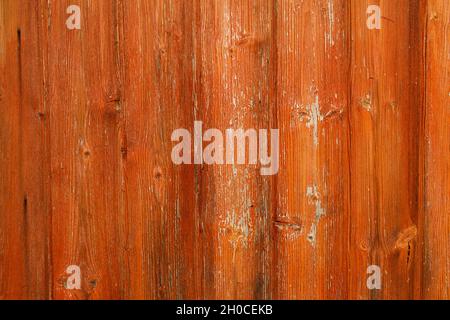 Textured wooden surface painted with orange paint, exfoliated under the influence of time and the environment. Texture, background. Stock Photo
