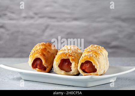 Sausages in dough on a plate against a brick wall background Stock Photo