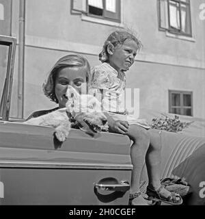 Ein Mädchen, ein Hund und eine junge Frau in einem Cabrio, Österreich 1930er Jahre. A little girl, a puppy and a young woman in a convertible, Austria 1930s. Stock Photo