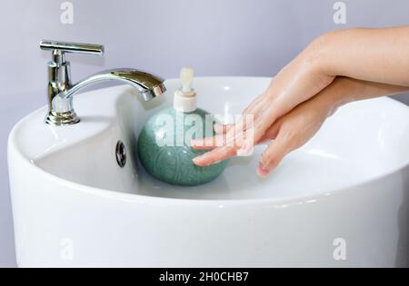 https://l450v.alamy.com/450v/2h0chb7/washing-hands-in-a-round-white-ceramic-basin-soap-bubbles-on-hand-there-is-a-green-liquid-soap-bottle-on-the-basin-and-water-is-flowing-from-the-tap-2h0chb7.jpg