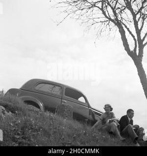 Ein junges Paar bei einer Pause am Straßenrand, Deutschand 1930er Jahre. A young couple having a break by the street, Germany 1930s. Stock Photo