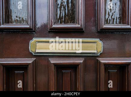 Front door of dark brown wood with traditional gold colored mailbox Stock Photo