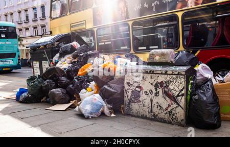 Brighton UK 12th October 2021 - Uncollected rubbish at recycling bins piles up in the North Street shopping area of  Brighton as the binmen strike continues in the city .  GMB members voted to strike in a dispute with the Green Party led city council over working practices including changes of duties and the removal of drivers from long-standing rounds. : Credit Simon Dack / Alamy Live News Stock Photo