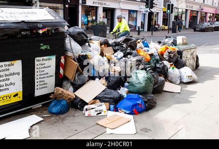 Brighton UK 12th October 2021 - Uncollected rubbish at recycling bins piles up in the North Street shopping area of  Brighton as the binmen strike continues in the city .  GMB members voted to strike in a dispute with the Green Party led city council over working practices including changes of duties and the removal of drivers from long-standing rounds. : Credit Simon Dack / Alamy Live News Stock Photo