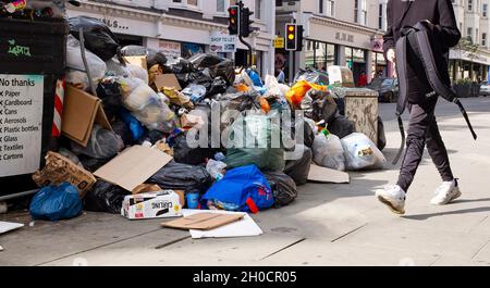 Brighton UK 12th October 2021 - Uncollected rubbish at recycling bins piles up in the North Street shopping area of  Brighton as the binmen strike continues in the city .  GMB members voted to strike in a dispute with the Green Party led city council over working practices including changes of duties and the removal of drivers from long-standing rounds. : Credit Simon Dack / Alamy Live News Stock Photo