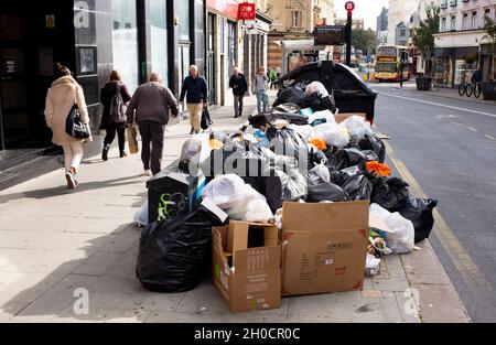 Brighton UK 12th October 2021 - Uncollected rubbish at recycling bins piles up in the North Street shopping area of  Brighton as the binmen strike continues in the city .  GMB members voted to strike in a dispute with the Green Party led city council over working practices including changes of duties and the removal of drivers from long-standing rounds. : Credit Simon Dack / Alamy Live News Stock Photo