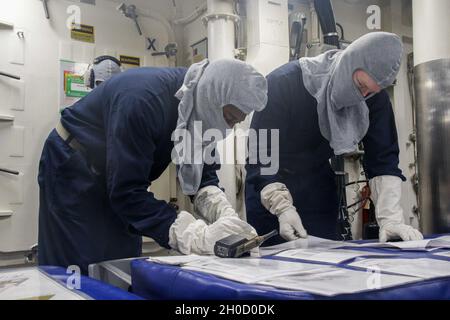 210127-N-FD648-1006 ATLANTIC OCEAN (January 27, 2021) – Ensign Samuel Jeune, left, and Ensign Daniel Shultz, review the zebra condition zone setting sheets during general quarters drill on the Arleigh Burke-class guided-missile destroyer USS Mahan (DDG 72), Jan. 27, 2021. Mahan is currently underway in the Atlantic Ocean conducting operations as part of the Dwight D. Eisenhower Carrier Strike Group. Stock Photo