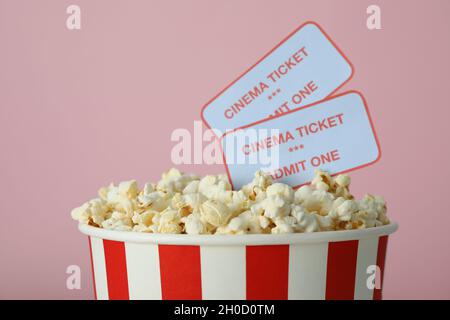 Paper cup with popcorn and tickets on pink background. Stock Photo