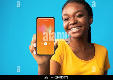 Music App. Cheerful Young Black Woman Demonstrating Audio Player Opened On Smartphone Stock Photo