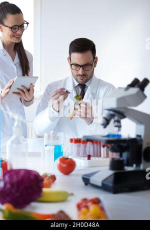 Two scientists working on vegetables with syringe in laboratory Stock Photo