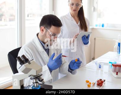 Two scientists working on vegetables testing with syringe in laboratory Stock Photo