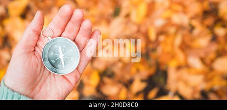 Compass lay on hand in the autumn forest. Selective focus. Shot from above. Point of view. Stock Photo