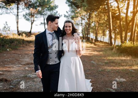 Portrait of a husband placing his arm over his wife's shoulder while walking through the woods Stock Photo