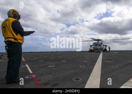 210129-N-UM706-1422 PHILIPPINE SEA (Jan. 29, 2021) Boatswain’s Mate 2nd Class Jeremiah Nortey, from Bronx, N.Y., signals an MH-60S Sea Hawk helicopter, from Helicopter Sea Combat Squadron (HSC) 25, aboard the amphibious dock landing ship USS Ashland (LSD 48). Ashland, part of the America Expeditionary Strike Group, along with the 31st Marine Expeditionary Unit, is operating in the U.S. 7th Fleet area of responsibility to enhance interoperability with allies and partners, serving as a ready response force to defend peace and stability in the Indo-Pacific region. Stock Photo