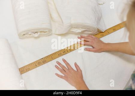 Female hands using wooden tailor ruler to measure cotton fabric. Textile  sale and sewing concept Stock Photo - Alamy