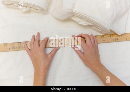 Female hands using wooden tailor ruler to measure cotton fabric. Textile  sale and sewing concept Stock Photo - Alamy