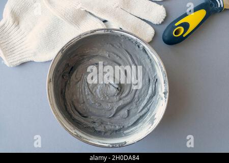 Worker equipment: container with cement, putty knife and workers gloves on a desk, top view Stock Photo