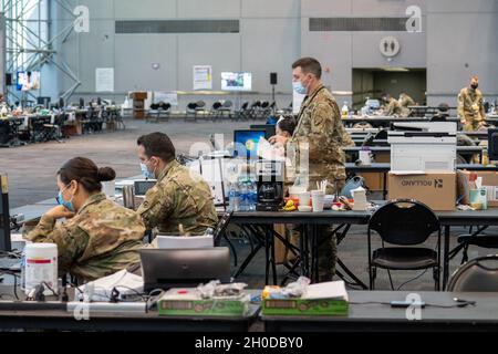 U.S. Army Soldiers with duties such as intelligence and personnel management, assigned to the 369th Sustainment Brigade, 53rd Troop Command, assign personnel and manage equipment, in support of state efforts to provide mass COVID-19 vaccinations administered by the New York State Department of Health at the Javits Convention Center in Manhattan, New York, January 31, 2021.    The National Guard has more than 350 Guardsmen and women deployed to the vaccination site to support staffing for the site. The New York State Department of Health conducts vaccination efforts for essential workers and me Stock Photo