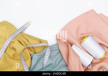 Various fabrics, measuring tape and thread isolated on white. Flat lay Stock Photo