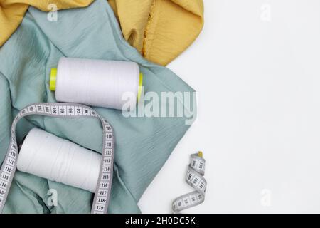 Various fabrics, measuring tape and thread isolated on white. Flat lay Stock Photo