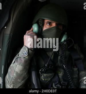 A Turkish Armed Forces soldier assigned to Regional Command-East, Kosovo Force, adjusts his headset during a UH-60 Blackhawk flight in Kosovo on Feb. 1, 2021. His platoon took a flight from Camp Bondsteel to be dropped off at a point along the administrative boundary line. The headset allows soldiers to communicate with the aircraft crew during the flight. Stock Photo