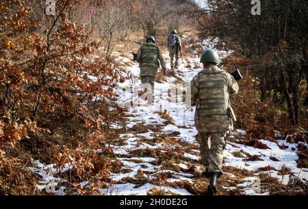 Turkish Armed Forces soldiers assigned to Regional Command-East, Kosovo Force, conduct a foot patrol along the administrative boundary line in Kosovo on Feb. 1, 2021. The platoon took a flight from Camp Bondsteel to be dropped off at a point on the ABL. The troops navigated steep inclines and thick foliage on a clear winter day. KFOR regularly patrols the ABL to maintain the safety and security of people in the region. Stock Photo