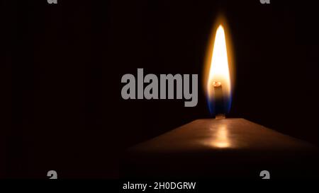 Single Burning Candle with Soft Glow in Darkness Stock Photo