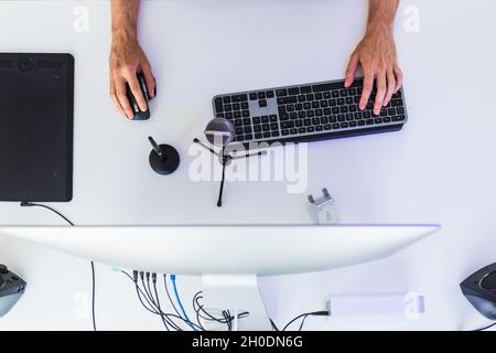 Anonymous male working on computer at table with graphic tablet Stock Photo