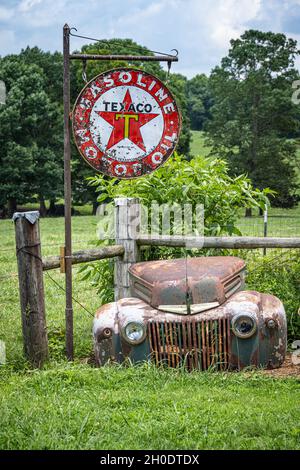 Vintage Texaco Gasoline & Motor Oil sign with the weathered front end of a classic Ford vehicle at Crazy Mule Art & Antiques in Lula, Georgia. (USA) Stock Photo