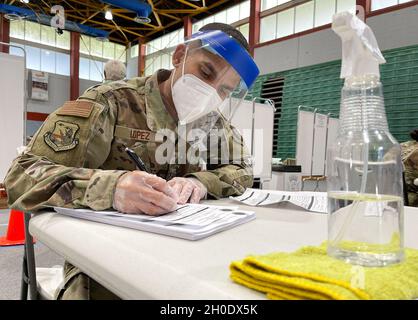 Airman 1st Class Jean López, an Air Force medical technician, writes down the COVID-19 vaccine information for one of his patients at the Pedrín Zorrilla Coliseum in San Juan, Puerto Rico, Feb. 4, 2021. The Puerto Rico National Guard, in support of the Department of Health, continued vaccinating the population over 65 years old as part of Operation Warp Speed. Stock Photo