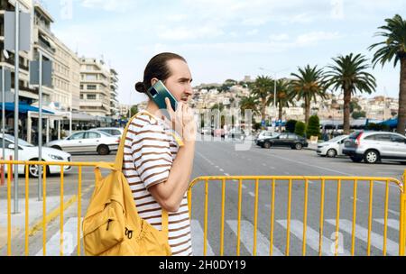 Young man with backpack walking on the street of city Kavala, Greece Stock Photo