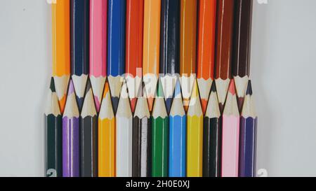 Many colored pencils are arranged around the edges of the image as a frame. In the center is an empty background with space for text. Stock Photo