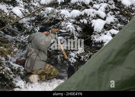 A paratrooper with 3rd Battalion, 509th parachute infantry regiment, 4th Infantry Brigade Combat Team (Airborne), 25th Infantry Division, secures his tent at Donnelley Training Area, Alaska, Feb., 7, 2021. Paratroopers will spend approximately ten days in the Alaskan cold conducting a near-peer combat scenario beginning with an airborne operation to secure an airfield. Stock Photo