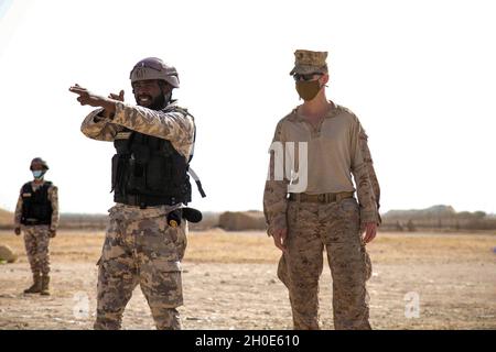 A U.S. Marine with Lima Company, 3rd Battalion, 1st Marines, attached to the Special Purpose Marine Air – Ground Task Force – Crisis Response - Central Command (SPMAGTF-CR-CC) 21.1 instructs a Qatari Marine on his sector of fire in Qatar, Feb. 07, 2021. The training was part of a subject matter expert exchange to strengthen ties between the two forces. The SPMAGTF-CR-CC is a crisis response force, prepared to deploy a variety of capabilities across the region. Stock Photo