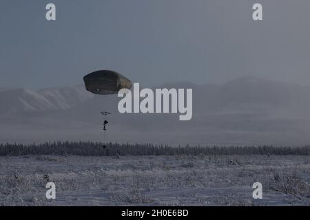 A paratrooper with 3rd Battalion, 509th parachute infantry regiment, 4th Infantry Brigade Combat Team (Airborne), 25th Infantry Division, prepares to land at Donnelley Training Area, Alaska, Feb., 7, 2021. Paratroopers will spend approximately ten days in the Alaskan cold conducting a near-peer combat scenario beginning with an airborne operation to secure an airfield. Stock Photo