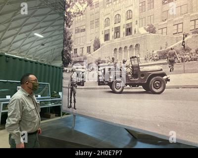 Tom Hara, Dreyer Field House manager passes a large photo of Little Rock Central High School and 101st Airborne Division (Air Assault) Soldiers who helped protect the Little Rock Nine after the Brown vs. Board of Education of Topeka. Some 600 101st Abn. Div. Soldiers assigned to 1-327th Airborne Bat-tle Group were deployed to protect the nine black students from protestors for about three months, said John O’Brien, director of the Brig. Gen. Don F. Pratt Memorial Museum. Stock Photo