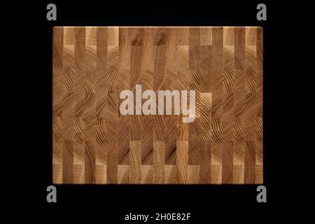 Mosaic texture of oak planks. Oak plank mosaic wooden chopping board on black background. Stock Photo