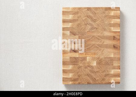 Oak spliced ​​wooden cutting board on burlap. The cross-section of the oak plank has a mosaic texture. Stock Photo