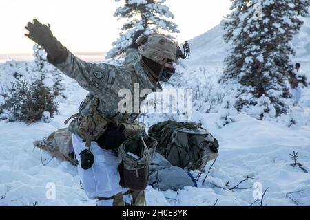 A paratrooper with 3rd Battalion, 509th parachute infantry regiment, 4th Infantry Brigade Combat Team (Airborne), 25th Infantry Division, stays warm by flapping his arms at Donnelley Training Area, Alaska, Feb., 7, 2021. Paratroopers will spend approximately ten days in the Alaskan cold conducting a near-peer combat scenario beginning with an airborne operation to secure an airfield. Stock Photo