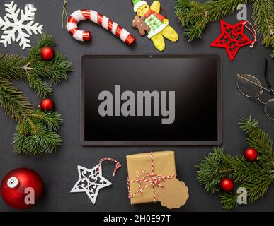 Christmas decoration and digital tablet on black background. Blank screen electronic device, copy space, greeting card template, top view Stock Photo