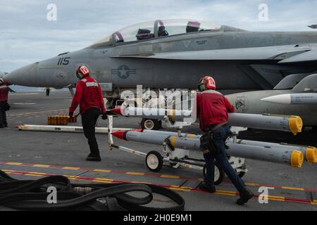 SOUTH CHINA SEA (Feb. 9, 2021) – U.S. Navy Aviation Boatswain’s Mate (Equipment) Airman Jacob Frazier, from Detroit, right, and Aviation Ordnanceman 2nd Class Geremy Hammond, from Baton Rouge, La., move AIM-20 missiles on the flight deck of the aircraft carrier USS Theodore Roosevelt (CVN 71) Feb. 9, 2021. The Theodore Roosevelt and Nimitz Carrier Strike Groups are conducting dual-carrier operations during their deployments to the 7th Fleet area of operations. As the U.S. Navy’s largest forward-deployed fleet, 7th Fleet routinely operates and interacts with 35 maritime nations while conducting Stock Photo