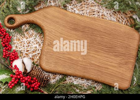 Wooden cutting board with fir tree branches lying in basket Stock Photo