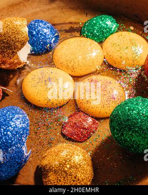 Close-up of egg yolks, egg white and broken egg shells covered with glitter in a pan Stock Photo
