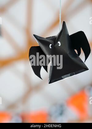 Origami bat made of black paper hanging on a rope for Halloween decorations. Dark paper ghost Halloween party concept origami paper bat. The figure of Stock Photo