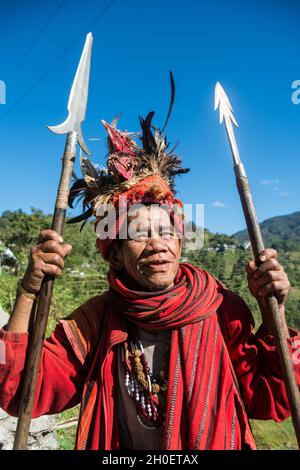 Senior Ifugao man in traditional costume. Banaue Rice Terraces in the background. Banaue, Ifugao province, Philippines Stock Photo