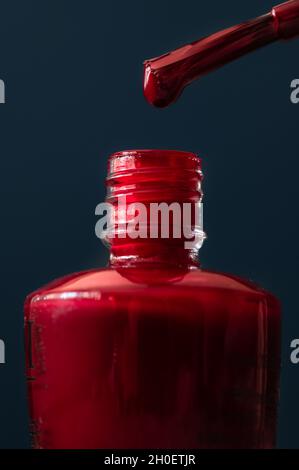 Red Nail Polish Dripping off Brush on Dark Background Stock Photo